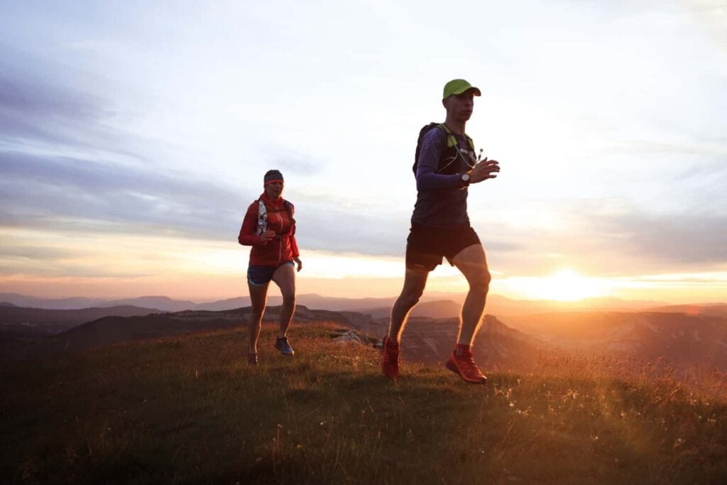 Two trail runners on a ridge at sunset