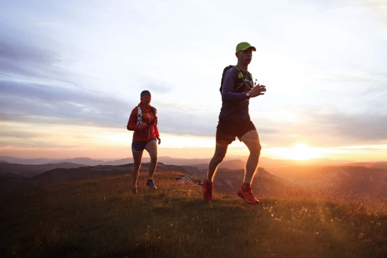 Two trail runners on a ridge at sunset