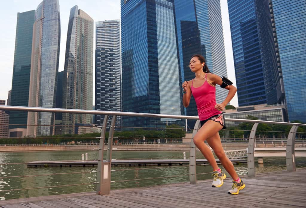 female runner crossing bridge city asia