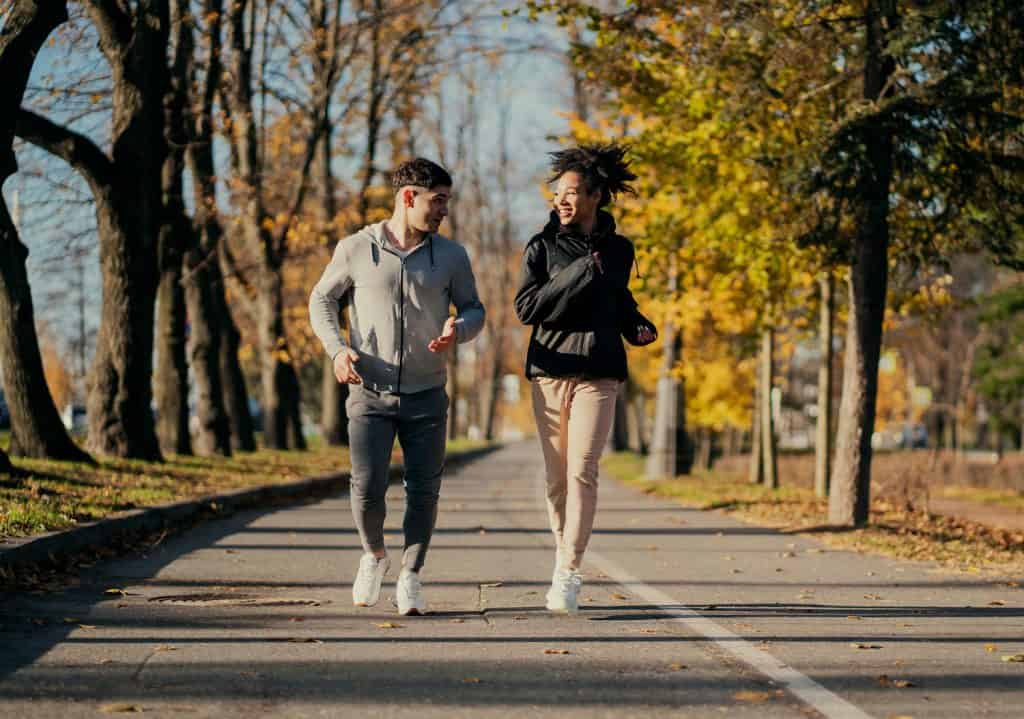 couple of young people running in autumn