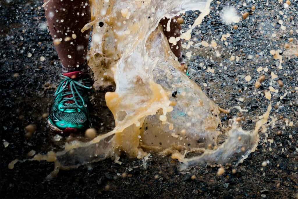 female trail runner running into a rain puddle