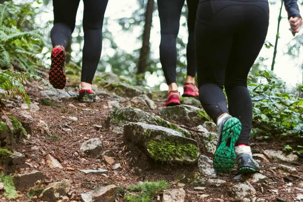 women in running shoes climbing a trail in the forest