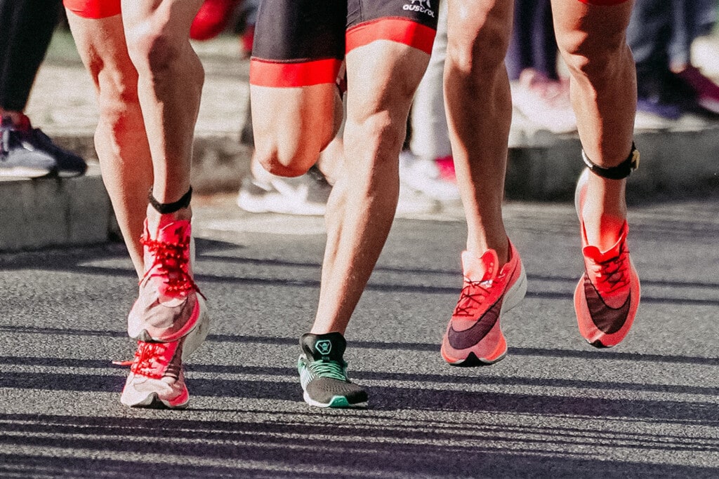 a close up of three men wearing marathon running shoes