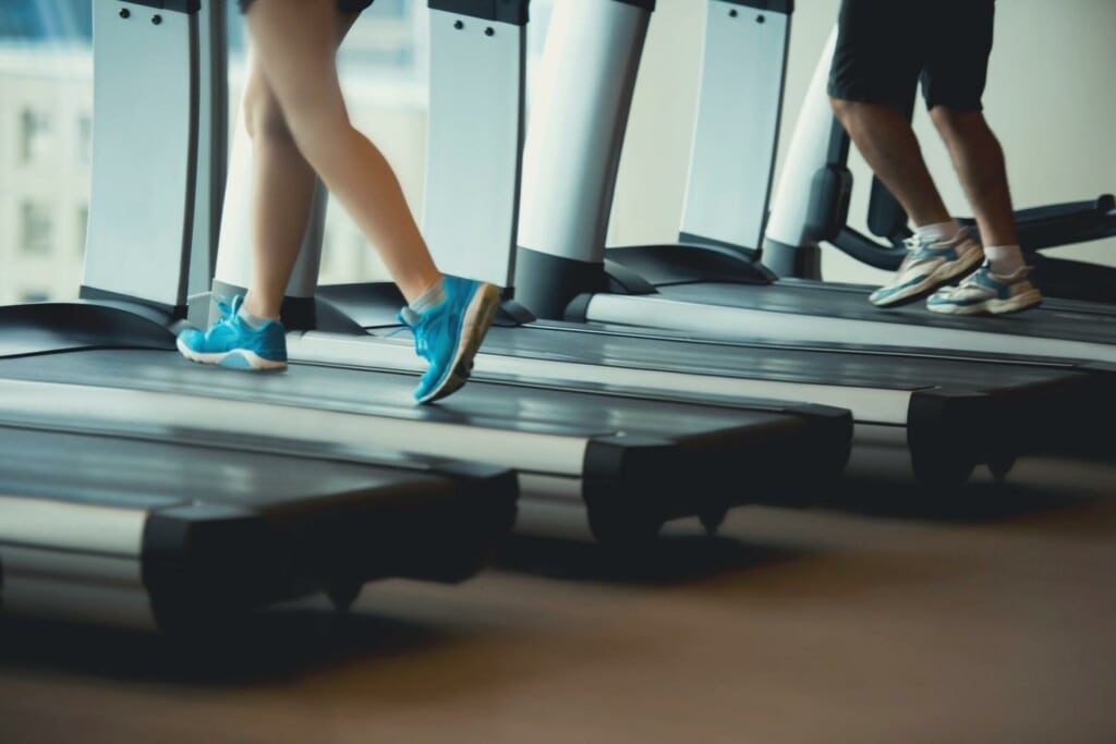 male and female runners on the treadmill in the gym during the day to prevent overuse injury