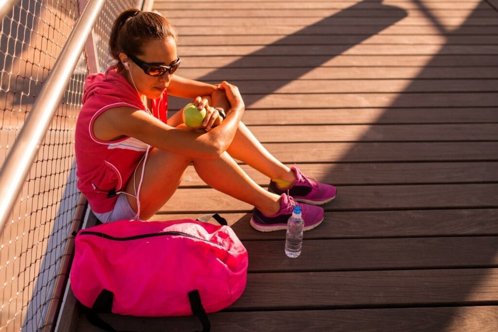 female runner resting and eating an apple