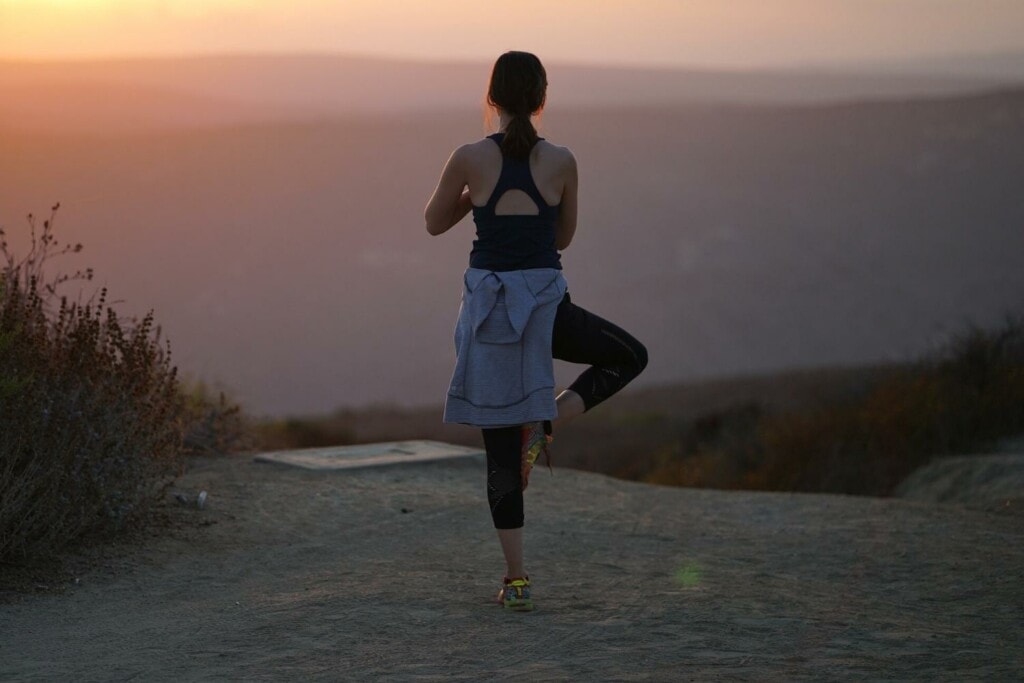 female runner practicing yoga at sunset 