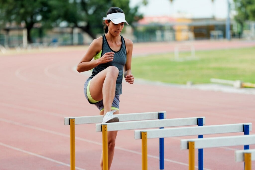 woman runner doing hurdle drills on the track
