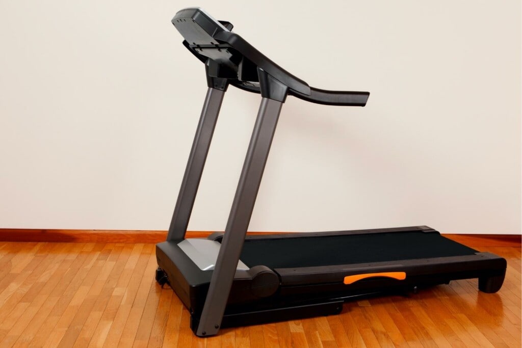 black treadmill in a room on a wooden floor