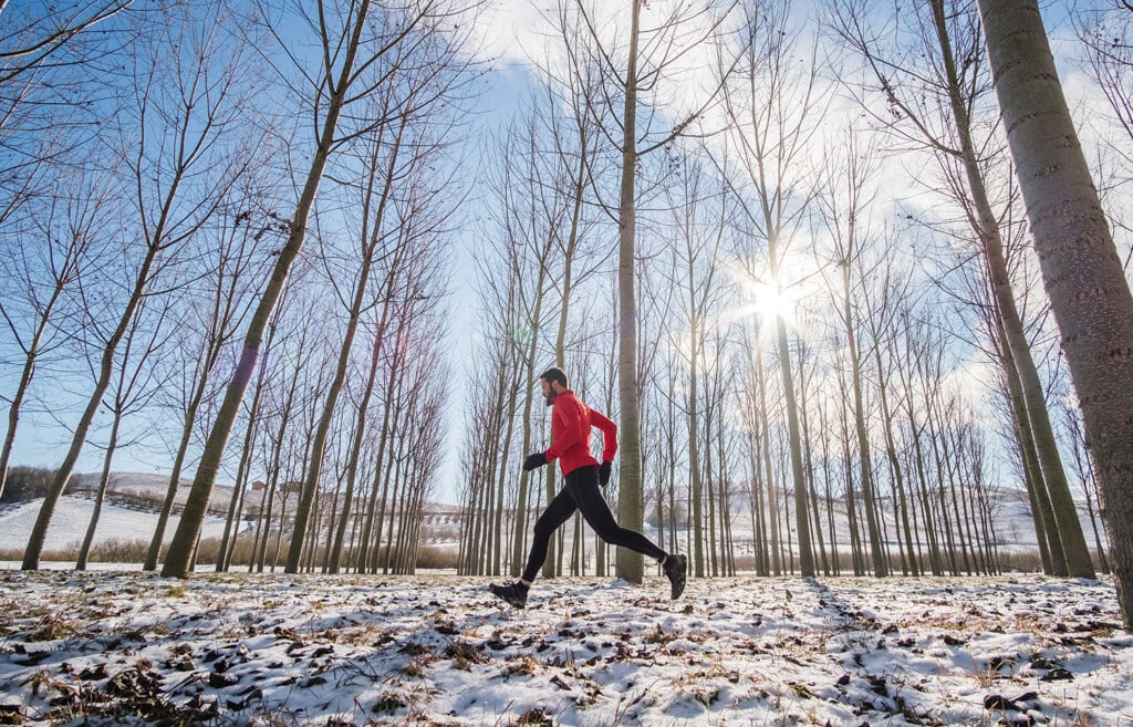 man running in forest on a sunny winter day