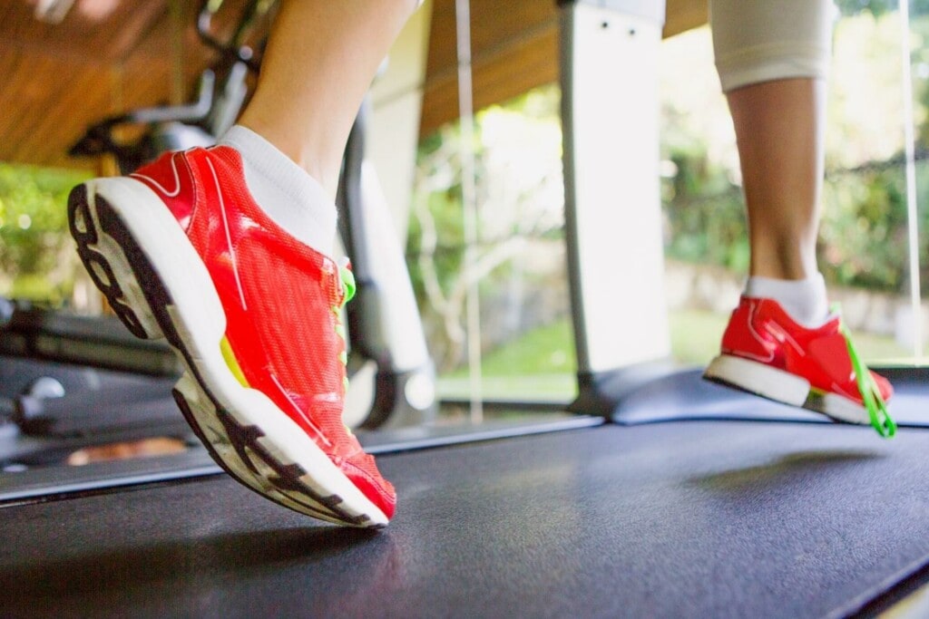 woman in red running shoes running fast on a treadmill