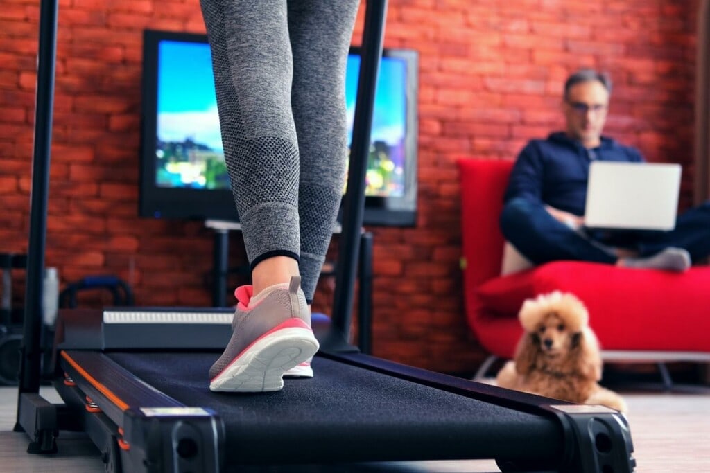 woman running on a treadmill with a dog and a man in a room