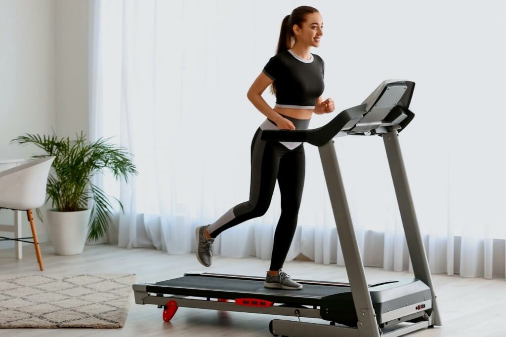 woman wearing sports clothing and shoes running on a treadmill at home