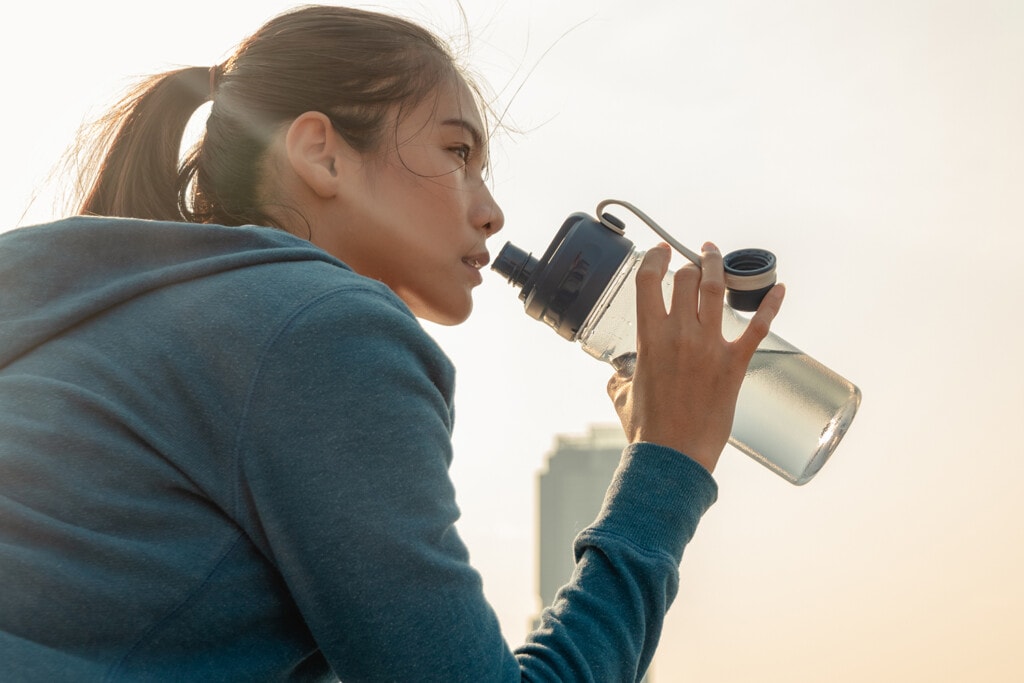 female runner drinking water after a run