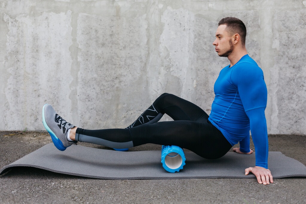 runner working on sore muscles with a roller to recover