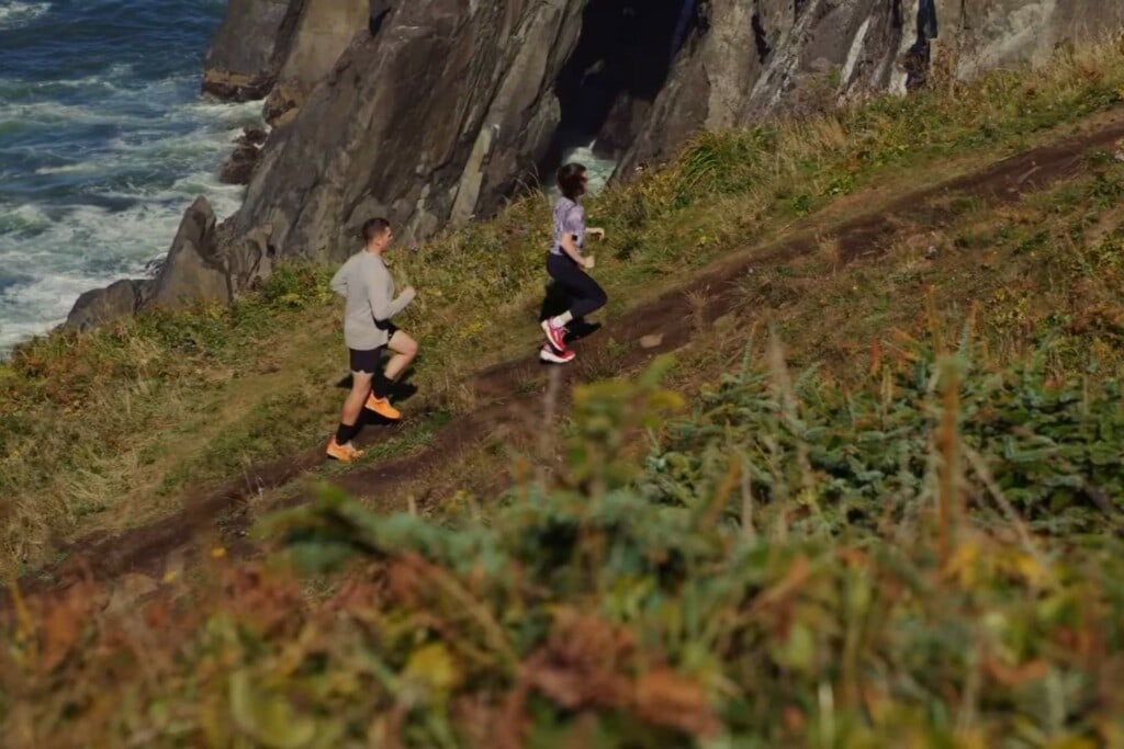 man and woman runners on a coastal trail wearing the Altra Olympus 5