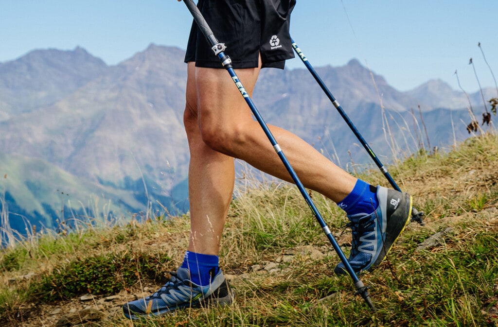 legs of a man with trekking poles wearing Salomon shoes