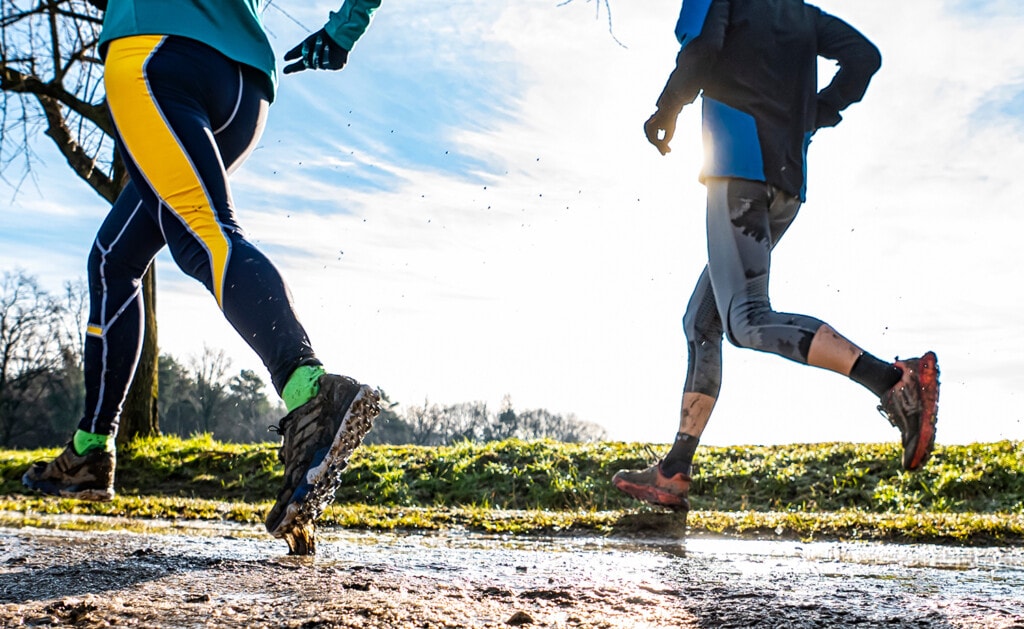 two people running on a muddy trail