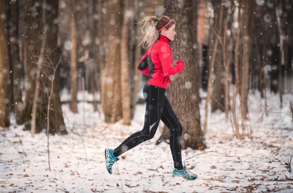 Young woman fitness model running in winter