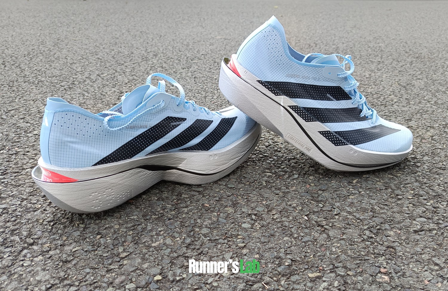 Pair of Adidas Adios Pro 5 on the road, showing the curved sole